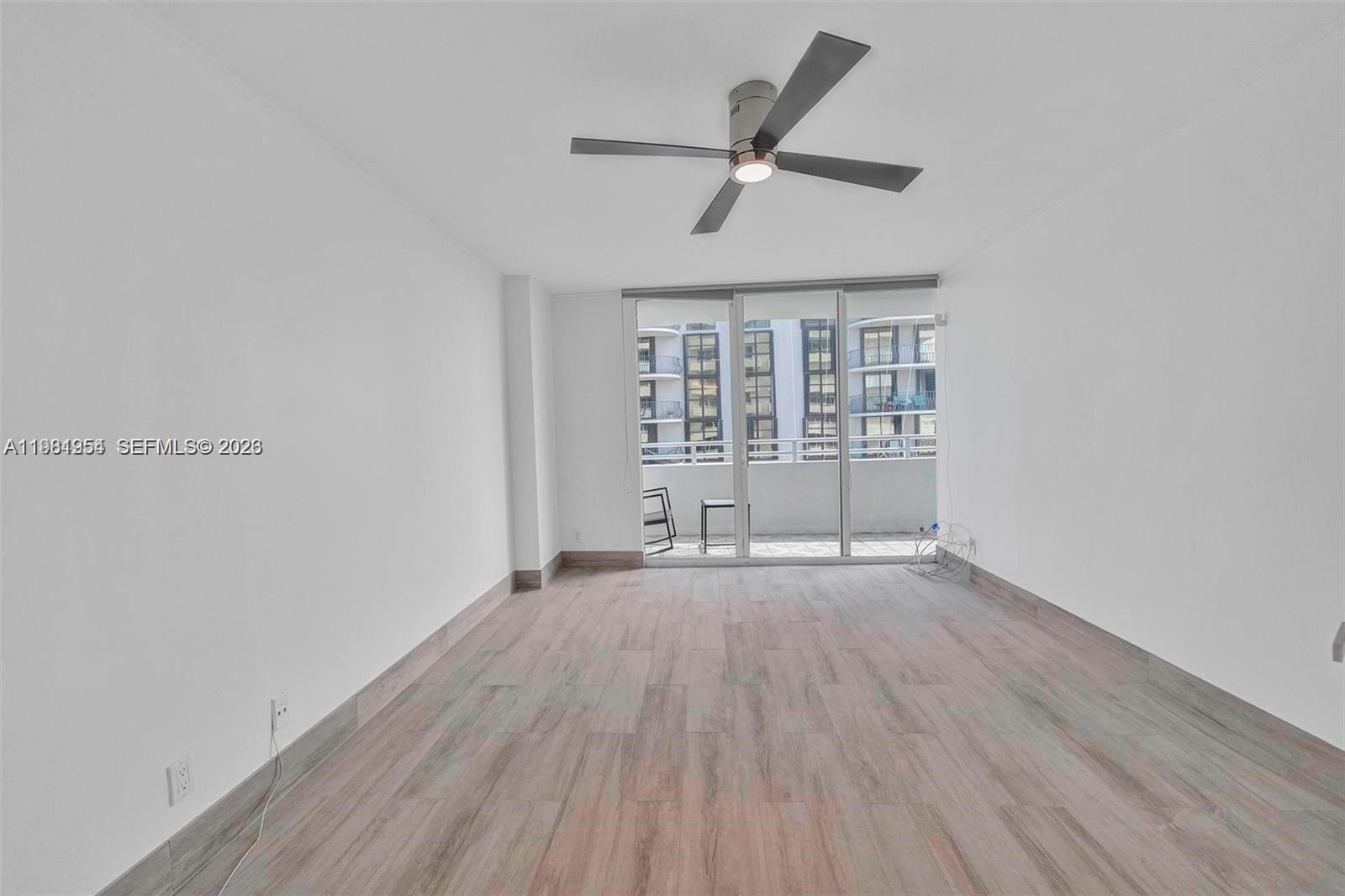 8911 Collins Avenue, Unit 703 Surfside, FL 33154 - Photo 8 of 24 an empty room with wooden floor and windows