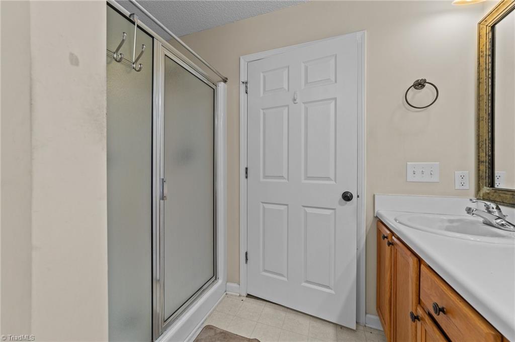 2852 WaterStone Loop High Point, NC 27265 - Photo 18 of 32 Primary bathroom with double bowl sink, tile flooring and separate shower.