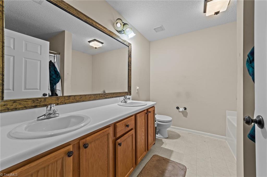 2852 WaterStone Loop High Point, NC 27265 - Photo 7 of 32 Primary bathroom with double bowl sink, tile flooring and separate shower.