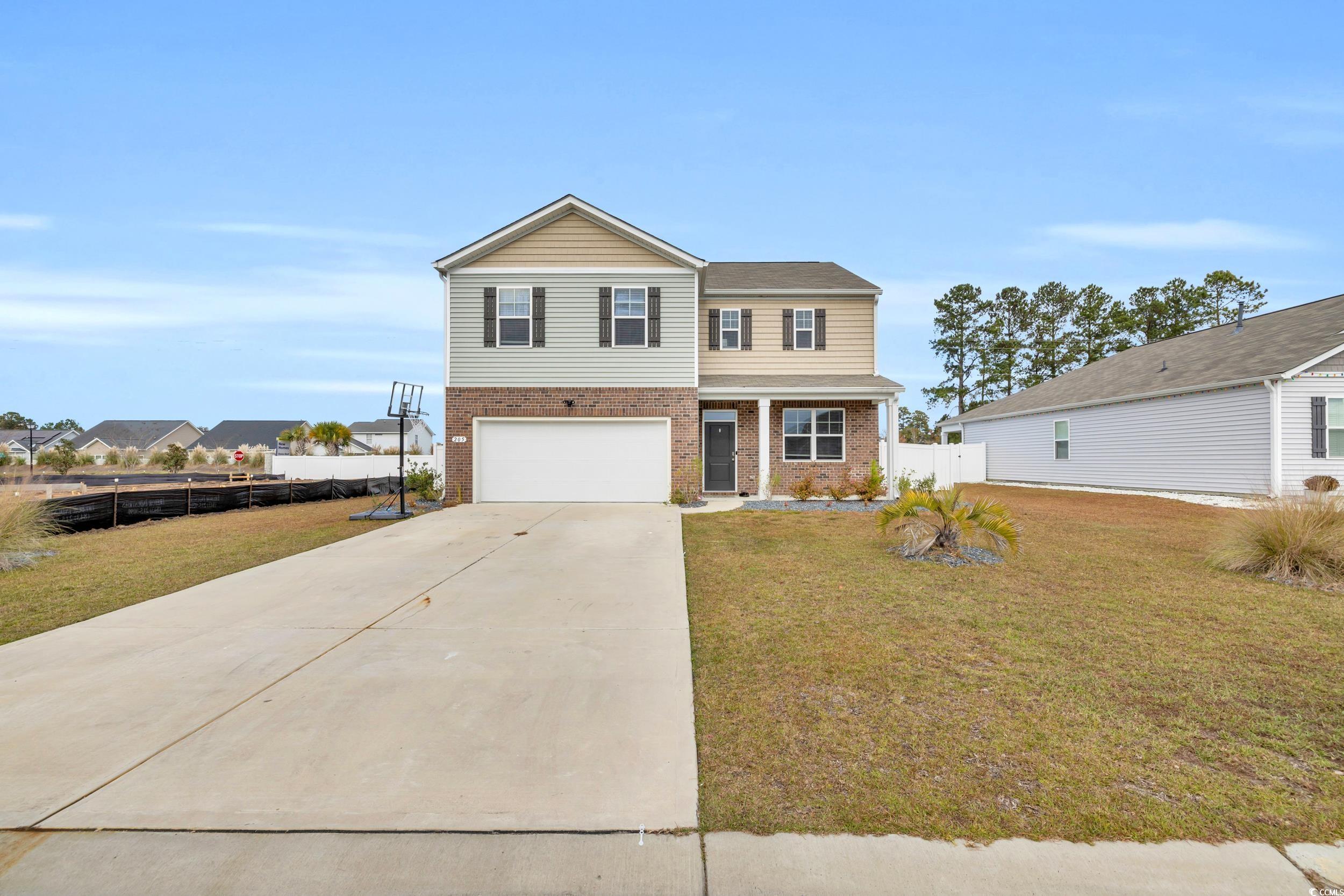 Traditional-style house featuring a porch, brick siding, concrete driveway, and an attached garage