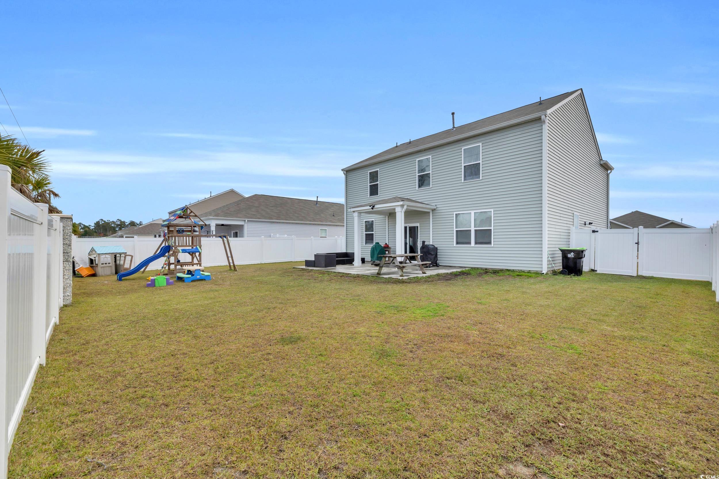 205 Black Pearl Way Myrtle Beach, SC 29588 - Photo 25 of 28 Back of property featuring a playground, a fenced backyard, and a patio area
