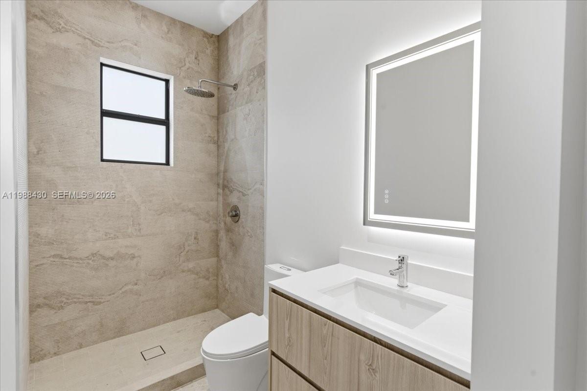 2925 Southwest 36th Avenue Miami, FL 33133 - Photo 33 of 59 a bathroom with a granite countertop sink toilet a mirror and shower