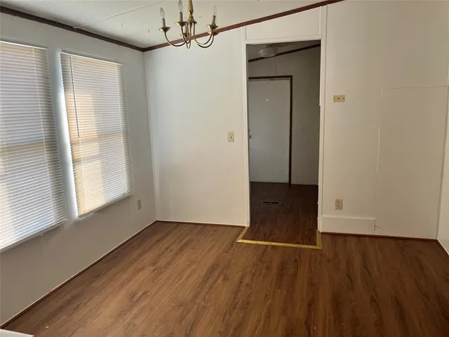 an empty room with wooden floor cabinet and windows