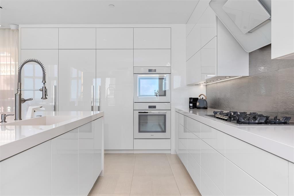 2140 North Ocean Boulevard, Unit V Fort Lauderdale, FL 33305 - Photo 25 of 63 a kitchen with granite countertop white cabinets and white appliances