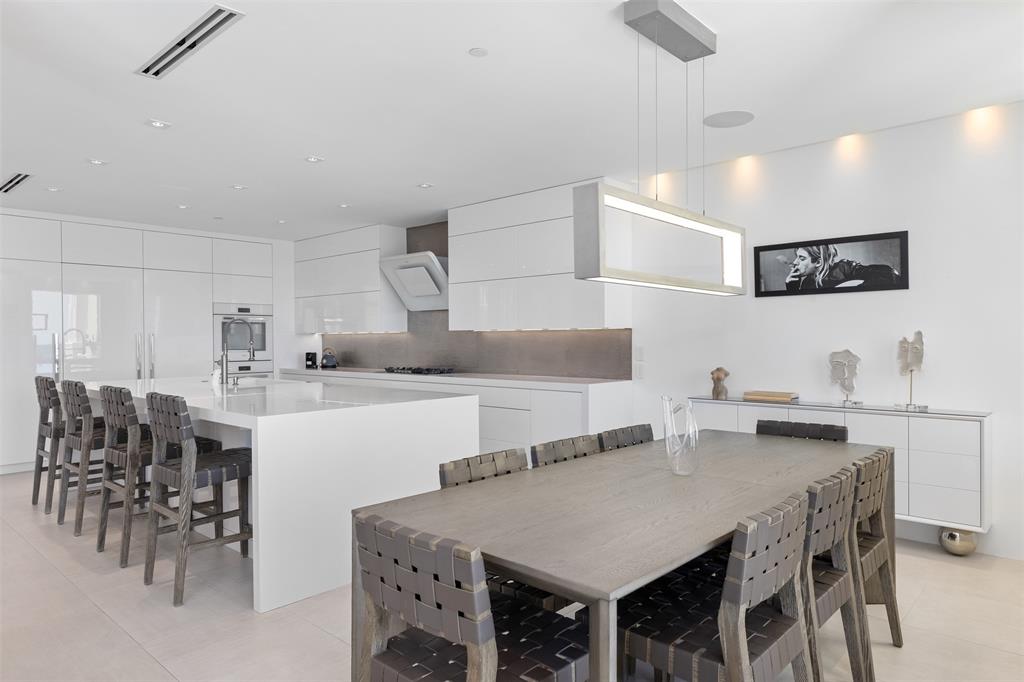 2140 North Ocean Boulevard, Unit V Fort Lauderdale, FL 33305 - Photo 26 of 63 a kitchen with kitchen island a dining table chairs and white cabinets