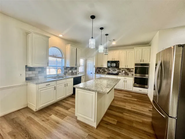 a kitchen with granite countertop white cabinets and stainless steel appliances