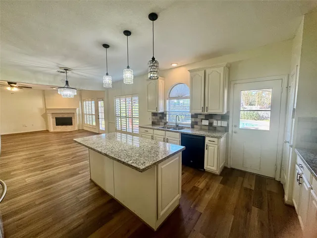 a kitchen with kitchen island granite countertop a stove and a wooden floor