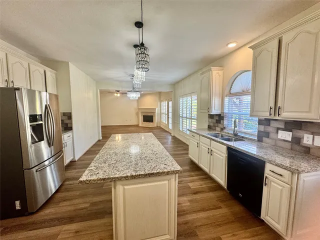 a large kitchen with stainless steel appliances granite countertop a stove refrigerator and cabinets