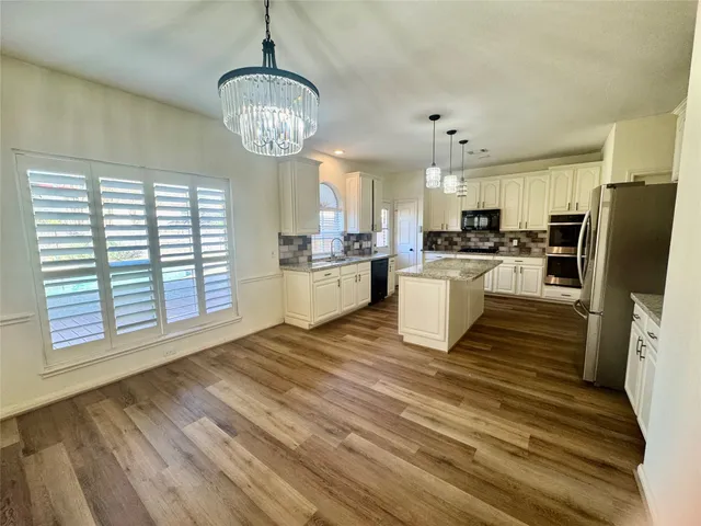 a kitchen with stainless steel appliances granite countertop a stove refrigerator and a view of living room