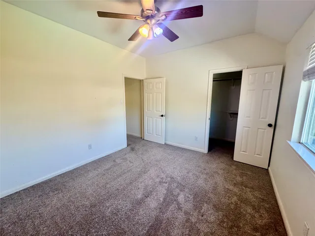 an empty room with closet and a chandelier fan