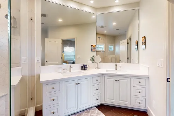 a spacious bathroom with a shower a sink and a mirror
