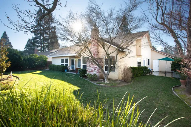 a view of a white house with a yard and a large tree