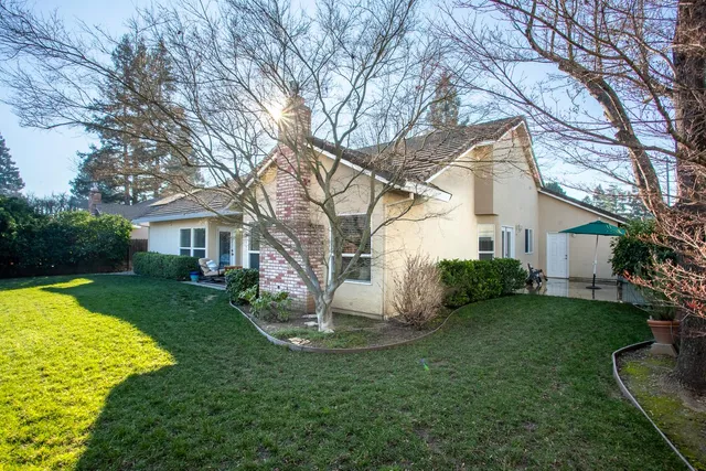 a backyard of a house with table and chairs under an umbrella