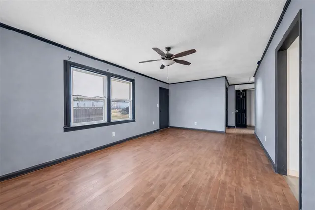 a view of an empty room with a window and wooden floor