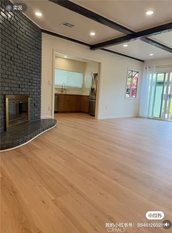 a view of an empty room with wooden floor and a fireplace
