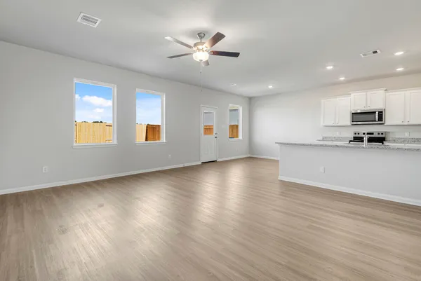 a view of empty room with wooden floor and ceiling fan