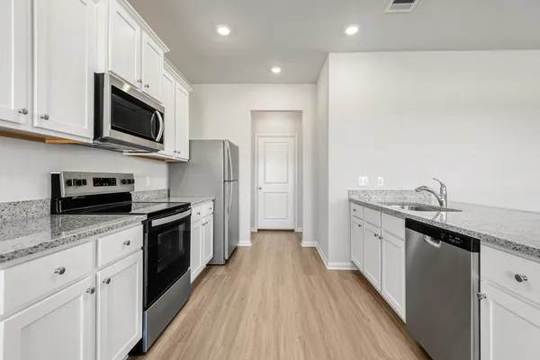 a kitchen with stainless steel appliances granite countertop a sink a stove top oven and wooden floors