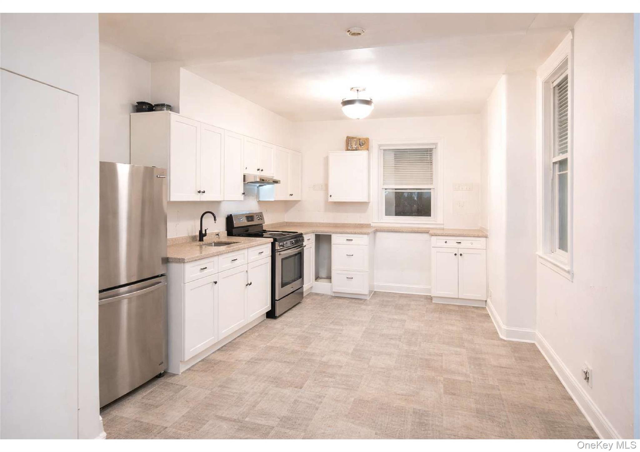 86-19 79th Street Queens, NY 11421 - Photo 7 of 19 a kitchen with white cabinets and white appliances