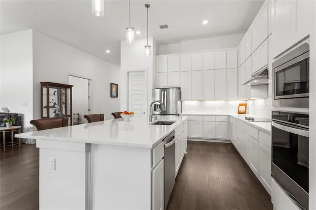 a kitchen with a sink a counter top space stainless steel appliances and cabinets