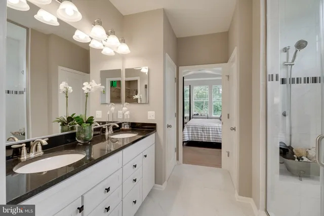 a spacious en suite bathroom with a double sink and mirror