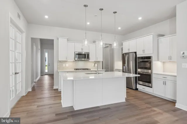 a large kitchen with stainless steel appliances kitchen island a large counter top and stove top oven