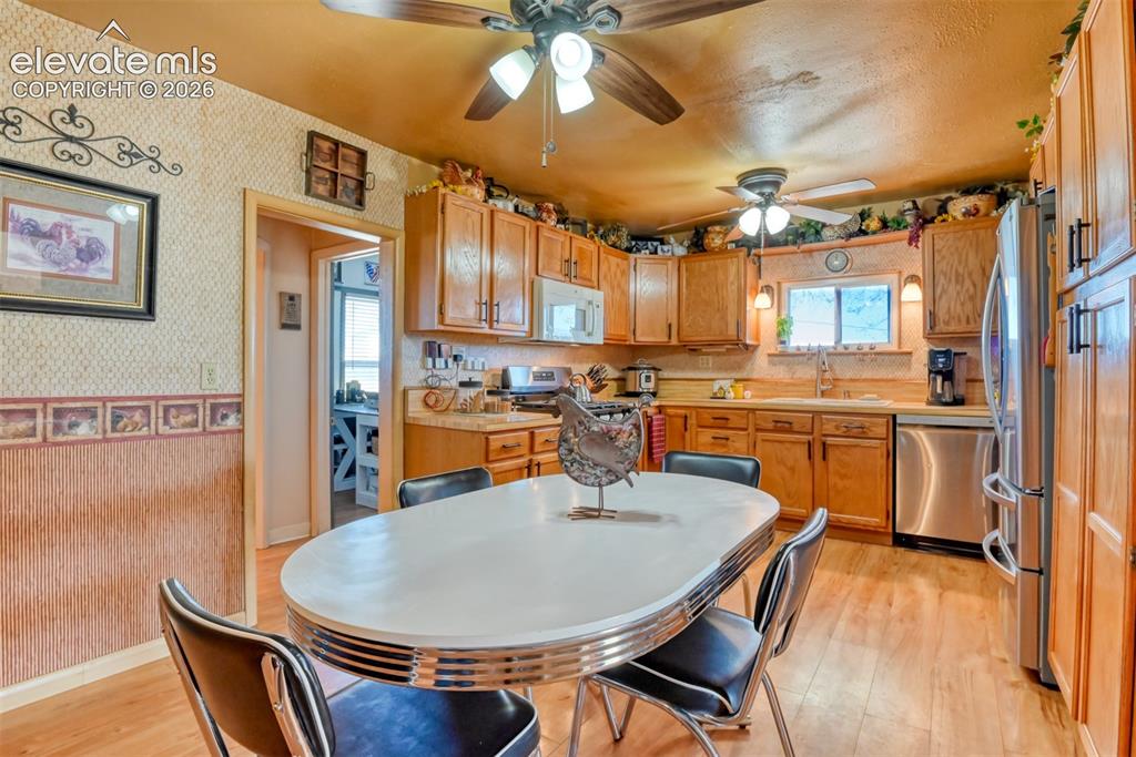 22558 Enoch Road Calhan, CO 80808 - Photo 31 of 50 a dining room with stainless steel appliances kitchen island granite countertop a stove a sink dishwasher and a refrigerator with wooden floor