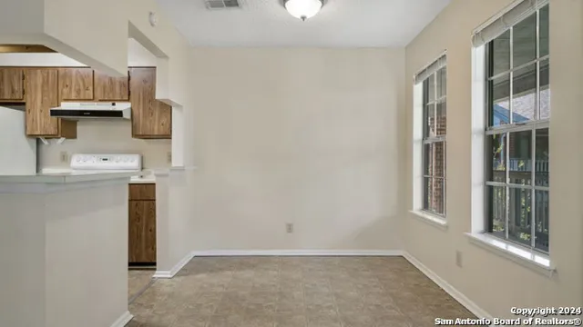 a view of a kitchen with a sink and dishwasher a refrigerator with white cabinets