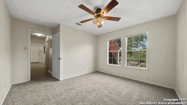 an empty room with windows and fan