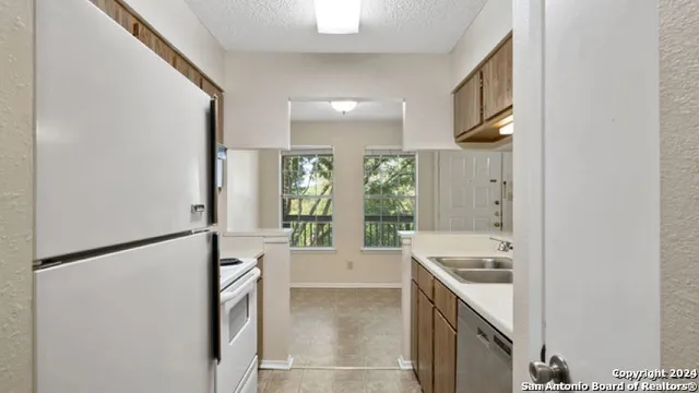 a large white kitchen with a sink and refrigerator