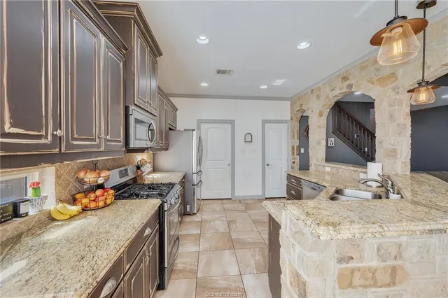 a kitchen with granite countertop a sink a stove and cabinets