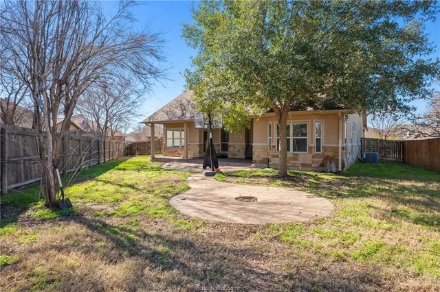 a view of a white house with a small yard and large tree