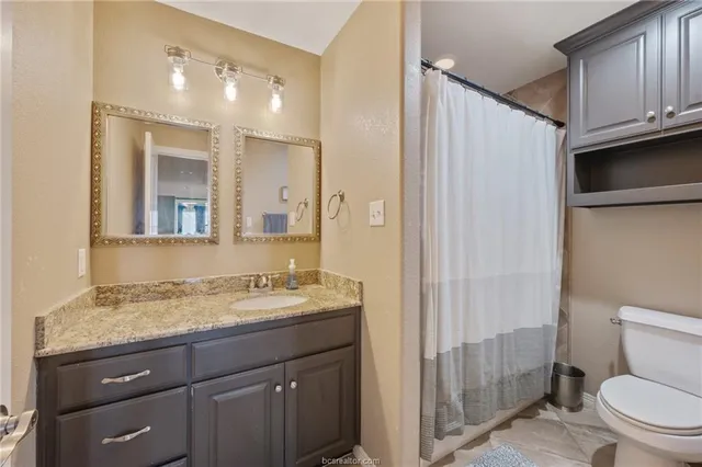 a bathroom with a granite countertop sink a toilet and a mirror