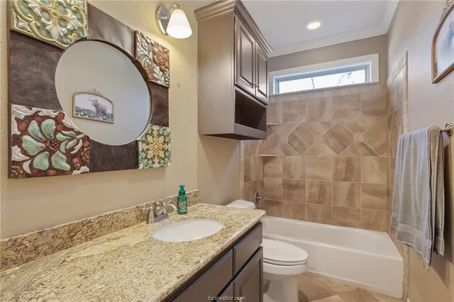 a bathroom with a granite countertop sink mirror toilet and bathtub