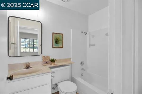 a bathroom with a toilet sink vanity tub and mirror