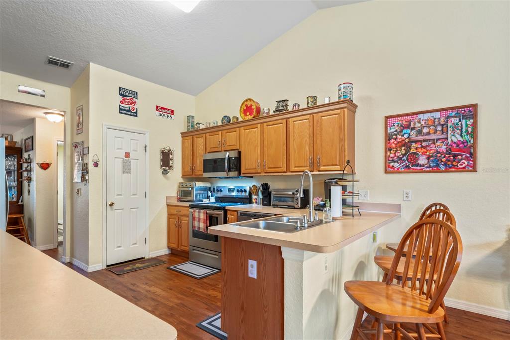 9086 Manchester Street Spring Hill, FL 34606 - Photo 15 of 50 a kitchen with stainless steel appliances granite countertop a stove a refrigerator a dining table and chairs