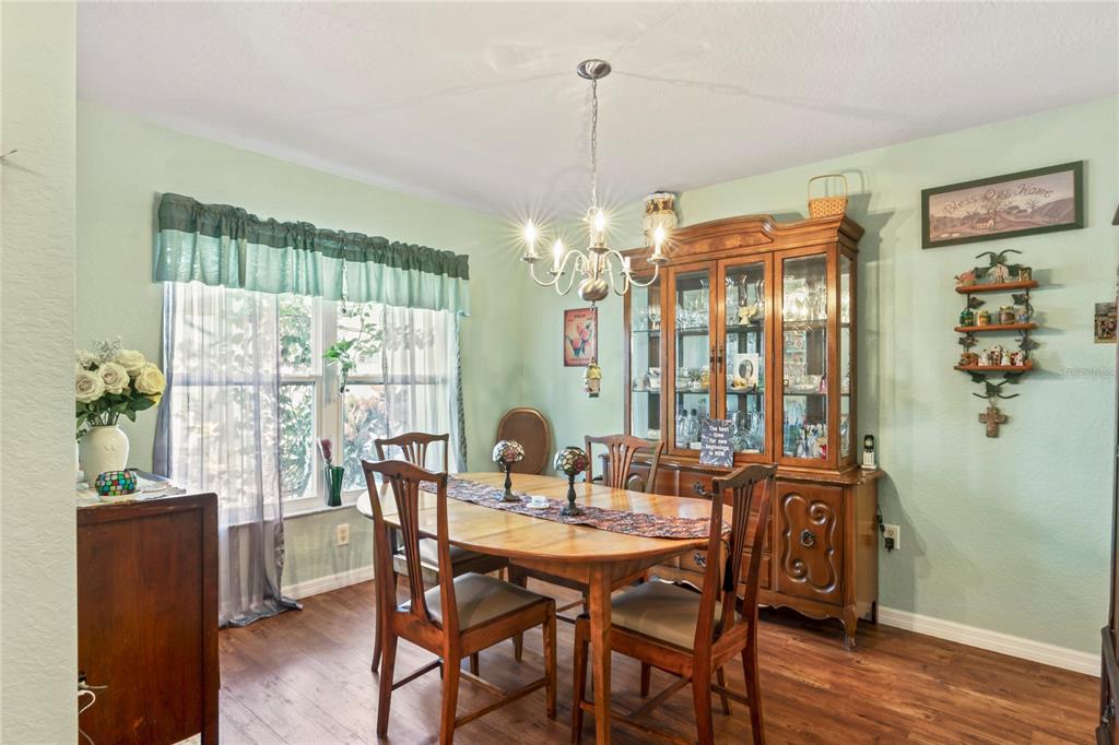 9086 Manchester Street Spring Hill, FL 34606 - Photo 21 of 50 a dining room with furniture a chandelier and wooden floor