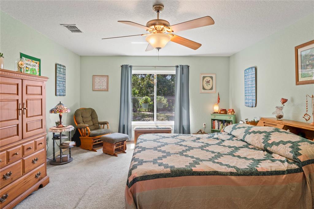 9086 Manchester Street Spring Hill, FL 34606 - Photo 24 of 50 a bedroom with a bed couch chandelier and a window