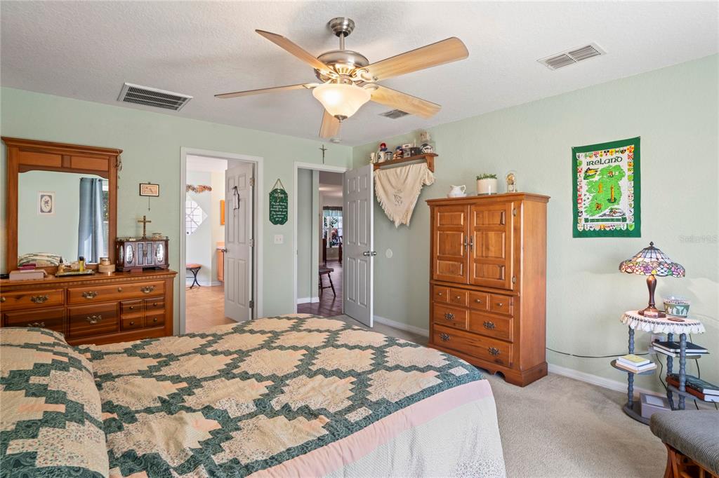9086 Manchester Street Spring Hill, FL 34606 - Photo 25 of 50 a bedroom with a bed a dresser and chair