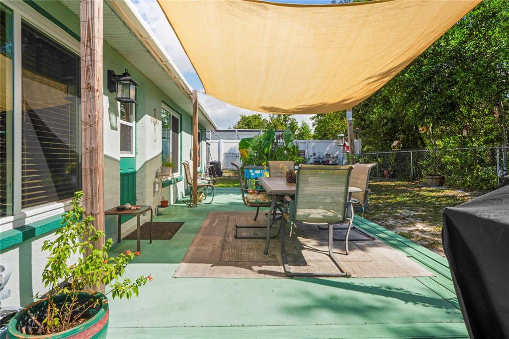 9086 Manchester Street Spring Hill, FL 34606 - Photo 35 of 50 a view of a patio with table and chairs potted plants and a large tree