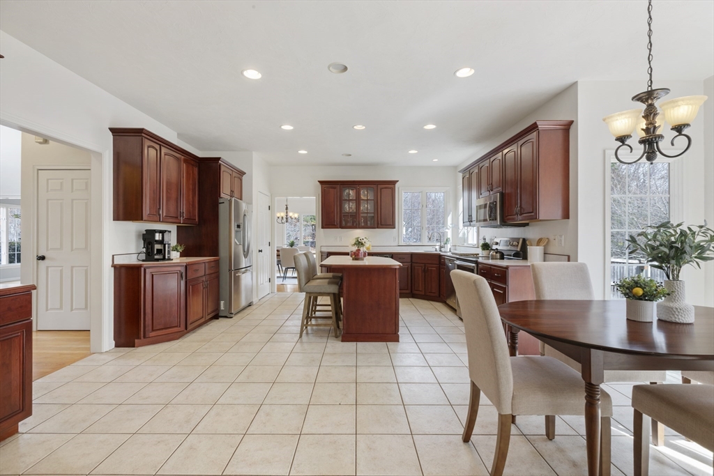 10 Anna Way Norton, MA 02766 - Photo 14 of 40 a kitchen with stainless steel appliances granite countertop a stove top oven a sink dishwasher a dining table and chairs with wooden floor