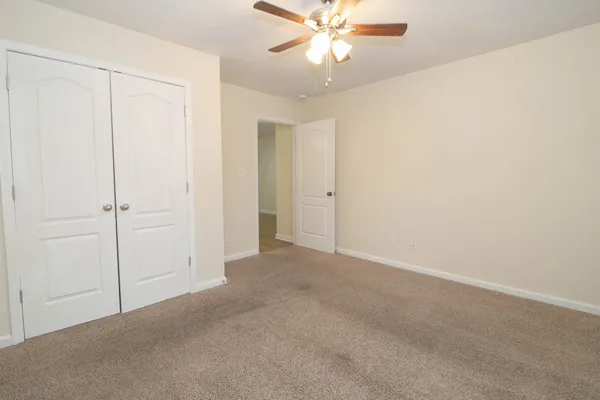 a view of an empty room and chandelier fan