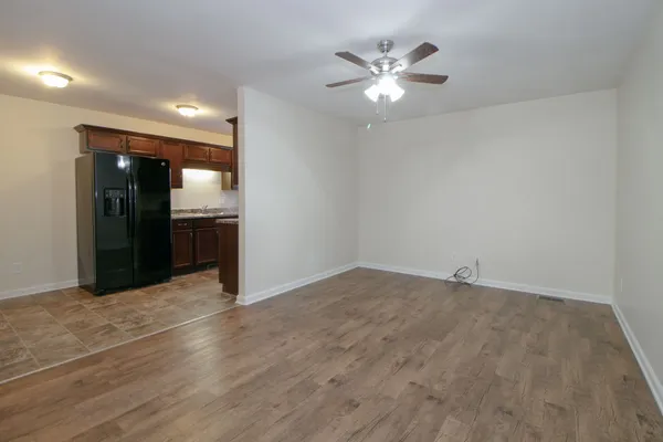 an empty room with wooden floor and chandelier fan