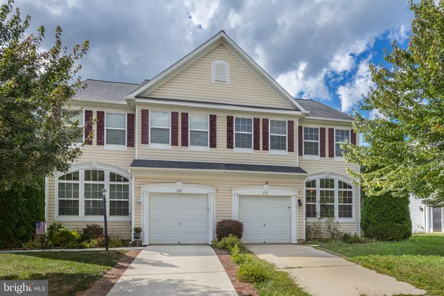 a front view of a house with a garden and trees