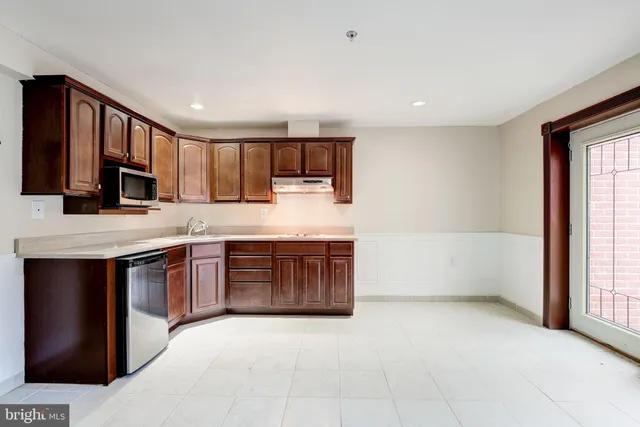a view of a white house next to a yard with potted plants