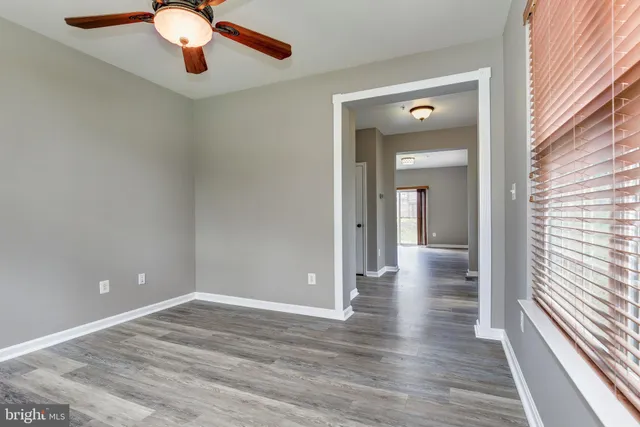 a view of an empty room with window and wooden floor