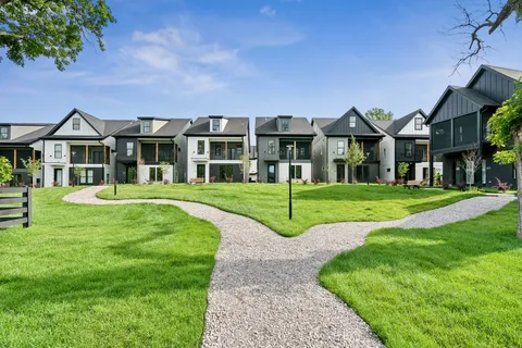 a view of a house with a big yard and large trees