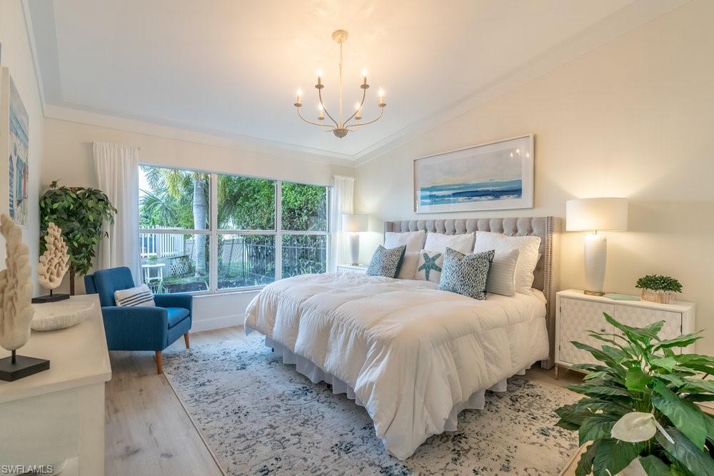 6831 Mill Pond Circle Naples, FL 34109 - Photo 10 of 45 a bedroom with a large bed and a chandelier