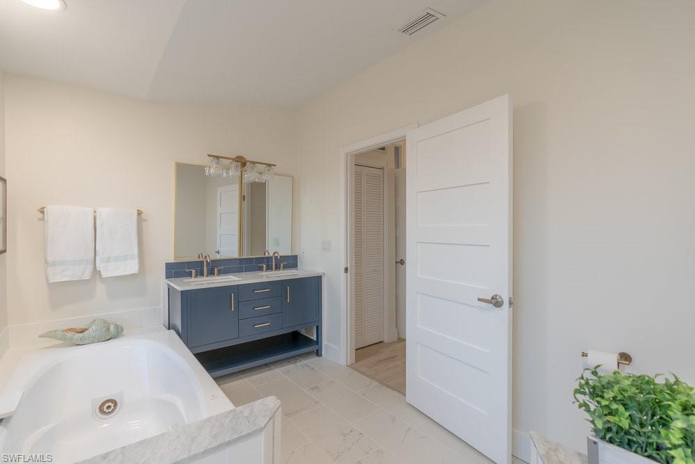 6831 Mill Pond Circle Naples, FL 34109 - Photo 12 of 45 a bathroom with a tub sink and mirror
