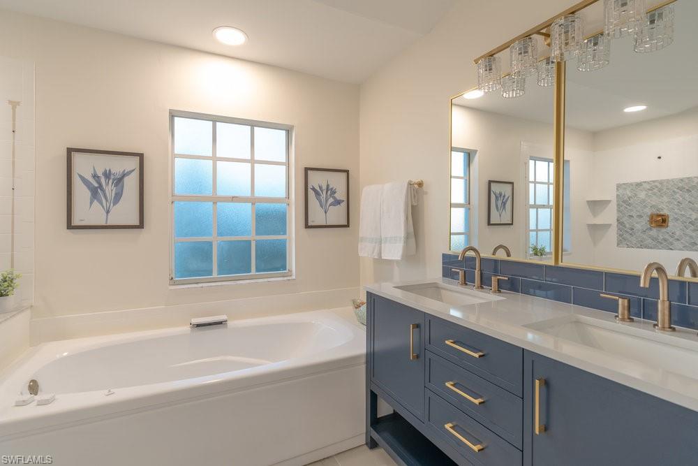 6831 Mill Pond Circle Naples, FL 34109 - Photo 13 of 45 a bathroom with a granite countertop sink mirror and a bathtub