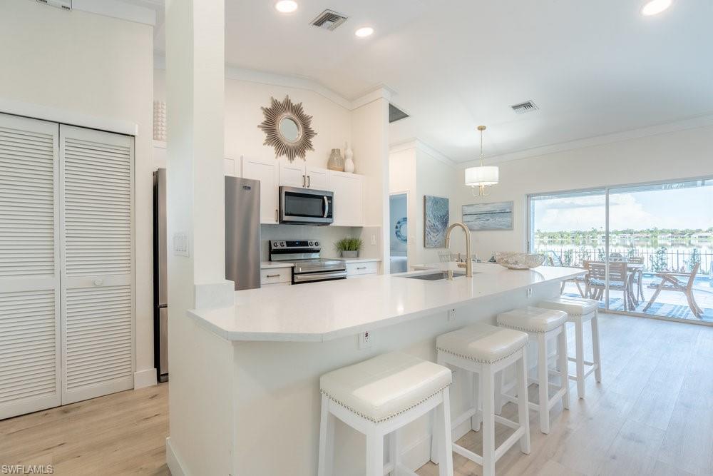 6831 Mill Pond Circle Naples, FL 34109 - Photo 6 of 45 a kitchen with stainless steel appliances a dining table chairs and granite counter tops